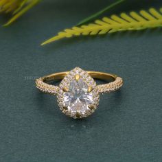 a diamond ring on a table next to some plants and leaves, with the center stone surrounded by small round diamonds