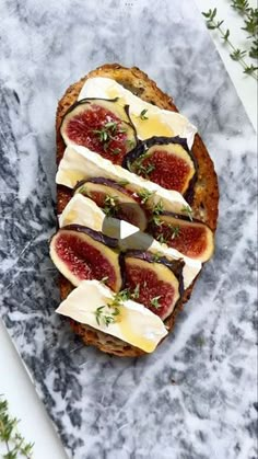 a piece of bread with cheese and figs on it sitting on a marble surface