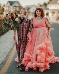 a man and woman are walking down the street in their wedding gowns with flowers