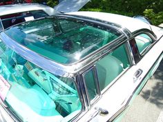 an old car with its hood open in a parking lot next to other cars and trees