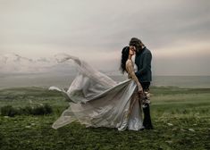 a man and woman standing on top of a lush green field