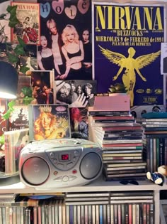 there is a cd player on top of the bookshelf in front of posters