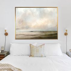 a large painting hangs above a bed with white sheets, pillows and throw pillows on it