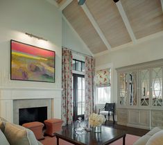 a living room filled with furniture and a painting hanging on the wall over a fire place