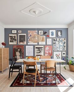 a dining room table with chairs and pictures on the wall behind it in front of an open door