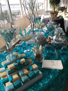 a table topped with lots of blue desserts and candies covered in frosting