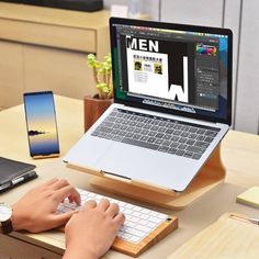 a person is typing on a keyboard in front of a laptop computer and cell phone