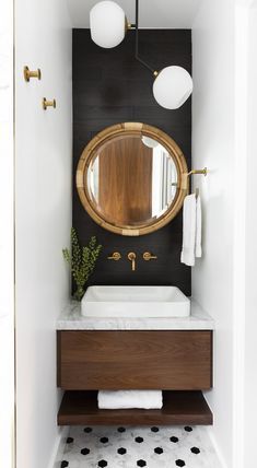 a bathroom with black and white tile flooring and a round mirror on the wall