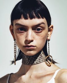 a woman with freckles on her neck wearing gold hoop earrings and chain choker