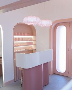 a pink and white counter in a room with two round lights hanging from the ceiling