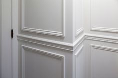 the corner of a room with white walls and paneling