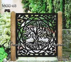 an iron gate with a tree on it in front of some bushes and trees behind it