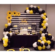 a black and white dessert table with sunflowers, cake and balloons on it