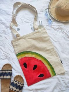 a watermelon tote bag and slippers on a bed with straw hats