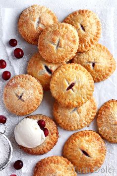 several small pies with faces drawn on them and cherries around the edges, sitting on wax paper