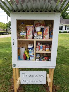 a white cabinet with some food in it and a sign that says take what you need