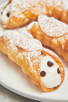 three pastries on a white plate covered in powdered sugar