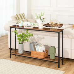 a living room with a couch, coffee table and potted plants on the side