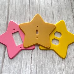 three little star shaped magnets sitting on top of a wooden table next to each other