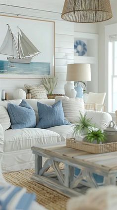 a living room filled with white furniture and blue pillows on top of it's couches