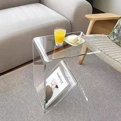 a glass table with a magazine on it in front of a couch and coffee table