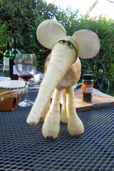 an elephant made out of food sitting on top of a table next to wine glasses