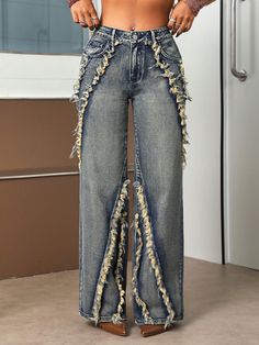 a woman in high waisted jeans with fringes on the bottom and side, standing next to a refrigerator