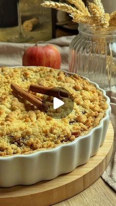 a pie sitting on top of a wooden cutting board next to an apple and oatmeal