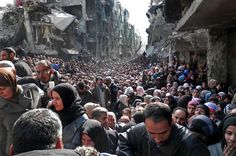 a large group of people standing around each other in the middle of a city street