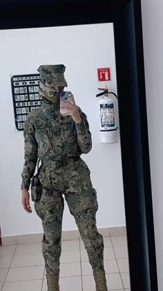 a woman in camouflage is taking a selfie with her cell phone while standing in front of a mirror