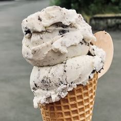 an ice cream cone with chocolate chip cookies and oreo chips on top, in front of a street