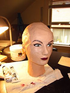 a mannequin's head sitting on top of a desk next to a lamp