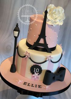 a three tiered cake with pink, white and black designs on top is decorated with the eiffel tower