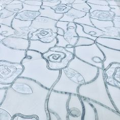 an artistically designed piece of glass in the shape of flowers and swirls on a white surface