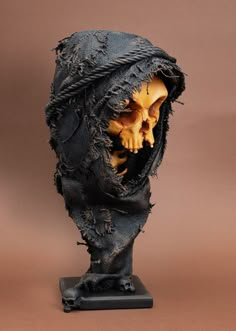 a sculpture of a human head covered in black cloth with yellow and orange skulls on it