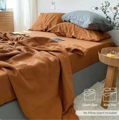 a bed with an orange comforter on top of it next to a night stand