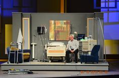 a man sitting on top of a stage next to a bed