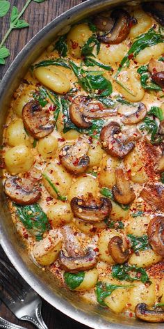 a pan filled with pasta and mushrooms on top of a wooden table