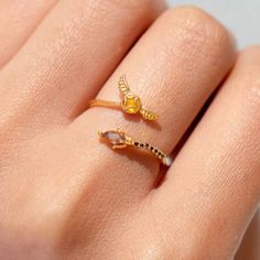 a woman's hand with two gold rings on it and one is wearing a diamond ring