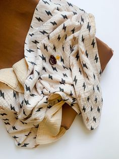 a white and black scarf laying on top of a brown pillow