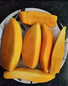 a white plate topped with sliced mangoes on top of a black and white table