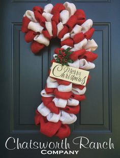 a red and white christmas wreath hanging on a door with the name charlotte ranch company written on it