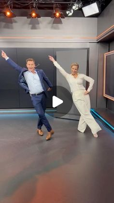 two people are dancing on the set of tv show, one is holding his arms up