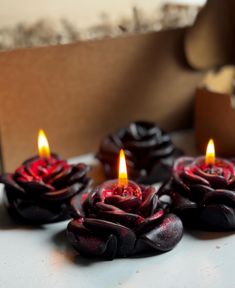 three candles with red and black flowers on them