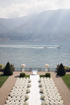 an outdoor ceremony set up with chairs and flowers on the lawn by the water's edge