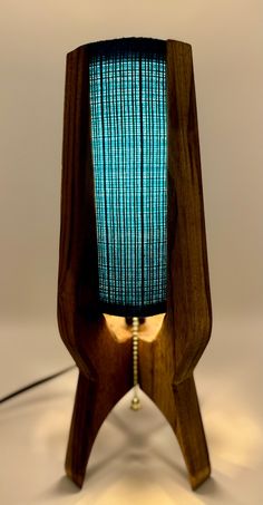 a wooden table lamp with a blue shade on it's side and a cord plugged into the base