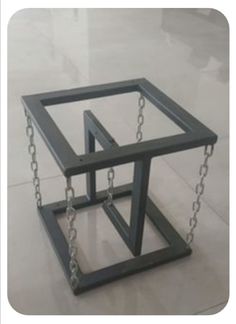 two metal frames with chains attached to them on the floor in front of a white wall