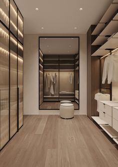 an empty walk in closet with clothes on hangers and white stools next to it