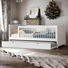 a white crib in a room with a christmas tree