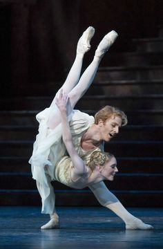 two ballerinas are performing on stage with one holding the other's leg